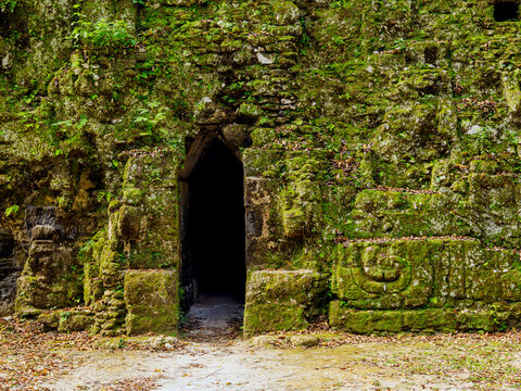 Exploring the entrance of Group G at Acanaladuras Palace in Tikal, Peten, Guatemala with moss-covered stone walls