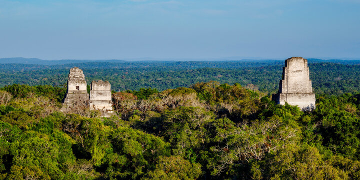 View from above showing Temples I, II, and III at Tikal surrounded by dense jungle in Guatemala