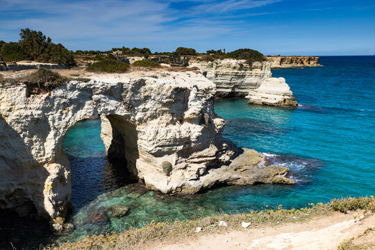 Views of Faraglioni in Salento with clear blue water and rocky cliffs on a sunny day in Italy