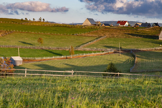 Rolling hills and simple houses in rural Romania showcase countryside life in Maguri village during evening light in Apuseni mountains