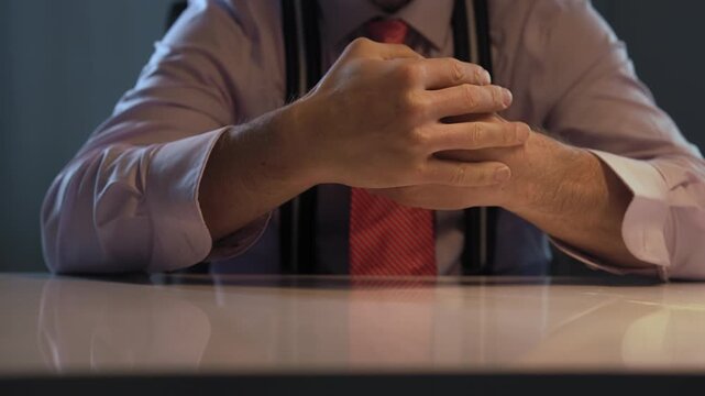 A businessman hands rest on the office desk as he prepares to make a decision