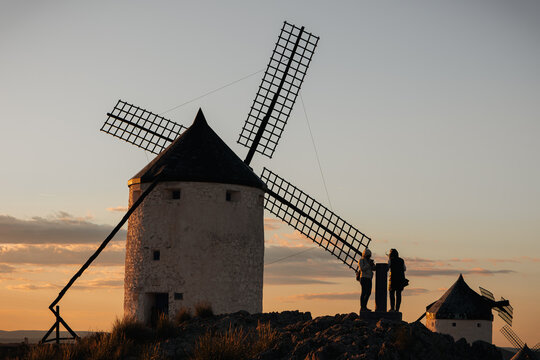 Consuegra windmills at sunset in Castile-La Mancha, Spain, two women admiring the iconic historical landscape