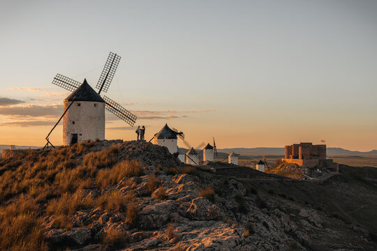Consuegra windmills and castle at sunset, iconic landscape evoking Don Quixote in Castile-La Mancha, Spain
