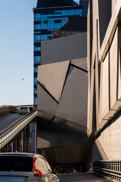 Angular urban architecture in Stockholm, Sweden rises beside an overpass ramp where shadow falls across a road, car lane and building facade
