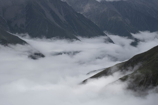 Low clouds and mist drift through mountain valleys in Sichuan, China during overcast light