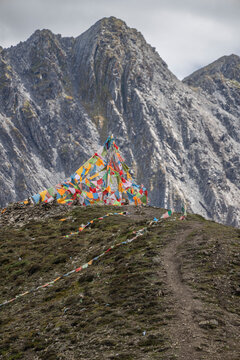 Zimei mountain pass shows prayer flags on a rugged path under dramatic clouds in Sichuan, China