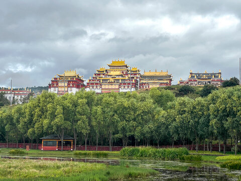 Songzanlin Monastery stands tall over wetland with clouds in Shangri-La City, Yunnan, China