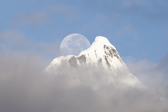 Full moon setting over Kawagebo peak in the Meili Mountains during early morning hours in Yunnan, China