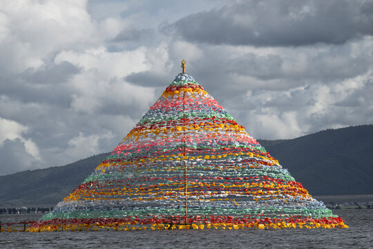 Colorful Tibetan stupa stands on Napa Lake as prayer flags flutter under cloudy skies in China