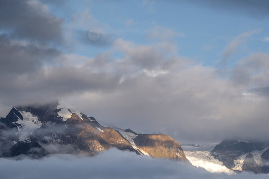 Sunlight breaks through clouds over Meili Mountains in Yunnan during early morning hours highlighting snow and rock