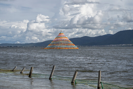 Colorful Tibetan stupa stands in Napa Lake with mountains and clouds in the background near Shangri-La in Yunnan, China