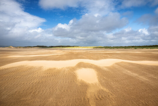 Strong wind shapes sand patterns across Whiteford Sands in Swansea, Wales