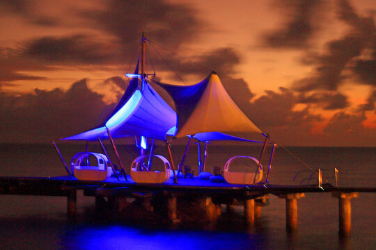 Scenic sunset lighting up the Coco de Mer hotel dock in Praslin, Seychelles with colorful tents