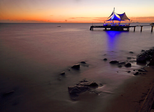 Beautiful sunset view over the water near Coco de Mer hotel in Praslin, Seychelles capturing a pier and ocean reflections