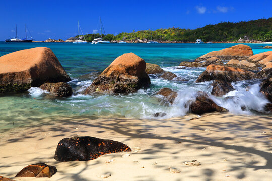Bright sun shines on rocks and turquoise water at Anse Georgette on a sunny day in Seychelles