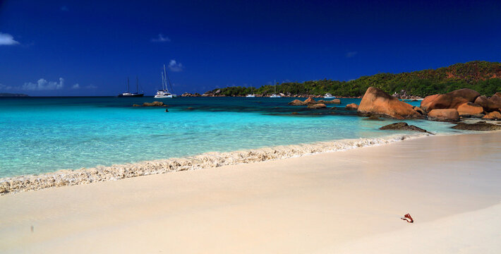Beach scene with boats and clear water on Praslin Island in Seychelles during a sunny day