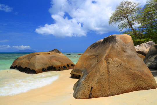 Explore Beau Vallon Beach in Mahe Seychelles with clear waters and large rocks along the sandy shore