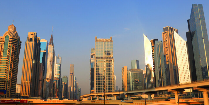 Modern buildings rise high in central Dubai with clear blue skies above during daylight hours in the United Arab Emirates