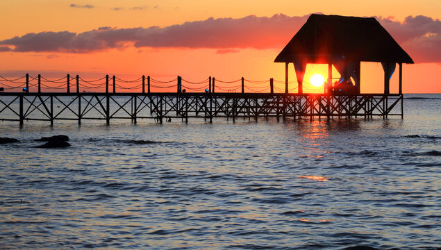 Sunset over the pier creating a vibrant scene with the sun setting behind the structure and reflecting in the water