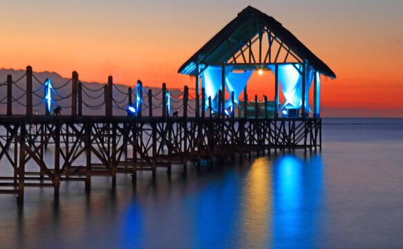 Colorful sunset view from the pier near the water at Pointe aux Piments in Mauritius with lights illuminating the structure