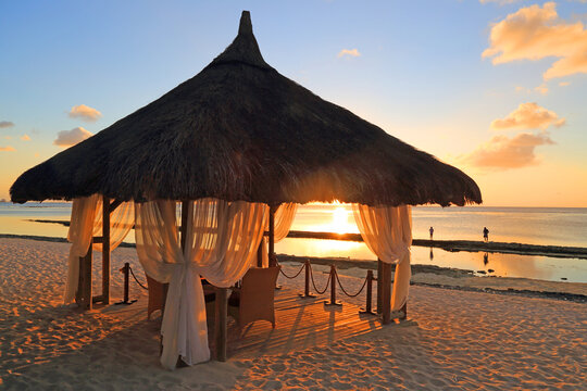 Wedding gazebo during sunset on a beach in Mauritius with calm waters and distant people by the shore