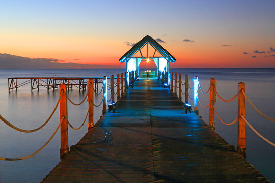 Sunset view over a pier with soft colors and lights in the water at Pointe aux Piments in Mauritius