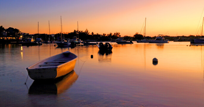 Sunset over calm waters with boats at Grand Baie, Mauritius during evening hours and vibrant colors in the sky