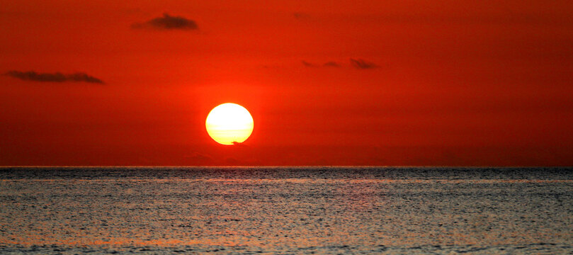 Sunset over the ocean in Mauritius, showcasing the sun setting on the horizon as the day ends and evening approaches with warm colors