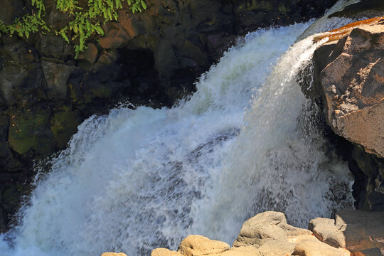 Water flows over rocks at Beau Champ Waterfall in Southern Mauritius during daylight hours