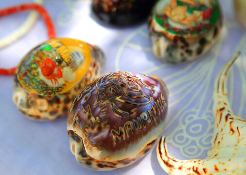 Colorful shells displayed at a market stall in Mauritius with detailed designs and local themes for sale