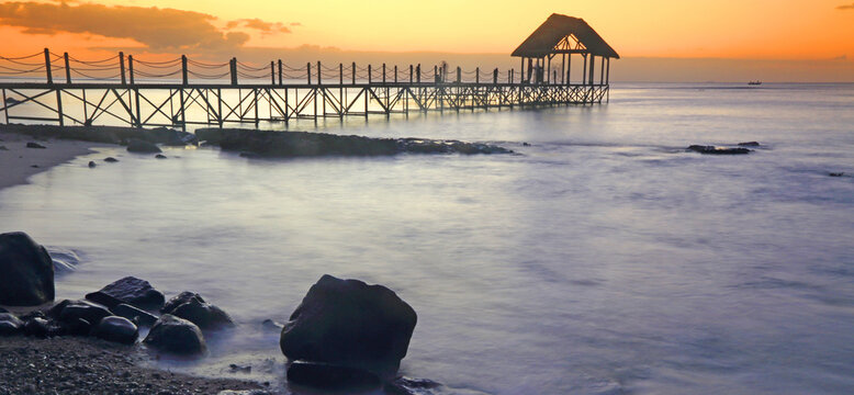Sunset view over a pier with clouds and water at Pointe aux Piments in Mauritius at dusk
