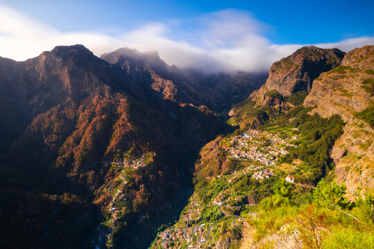 View from Eira do Serrado shows mountains, valleys, and town under sunset in Madeira's natural scenery