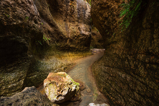 Solitary rock in shallow stream at Barranco de Luna with sandstone walls in Granada, Andalusia, Spain