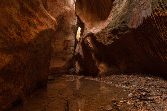 Stream flows through red-rock corridors in Barranco de Luna, Villanueva Mesa, Granada, Andalusia, Spain