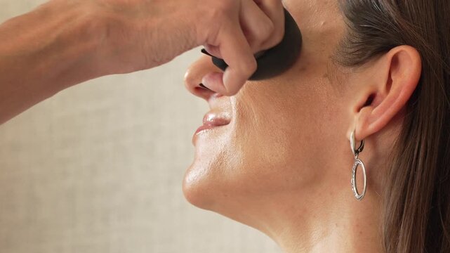 Makeup foundation beauty, professional artist applies liquid foundation to woman's face with a sponge for perfect skin