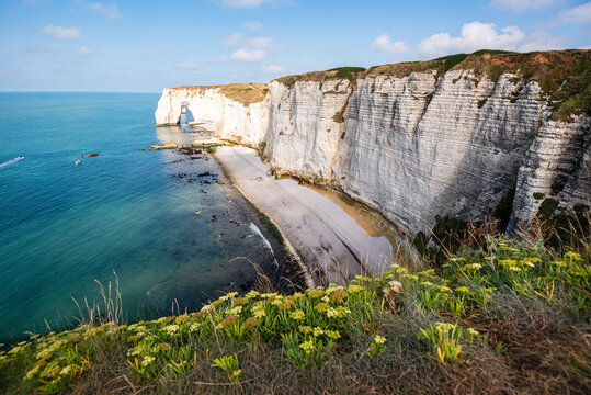 View of white chalk cliffs and turquoise sea in Etretat, Normandy during bright summer light over Alabaster Coast