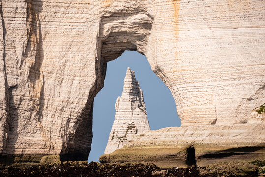 Framing LAiguille through Porte dAval arch at Etretat on the Alabaster Coast in Normandy, France, during daytime with clear sky conditions