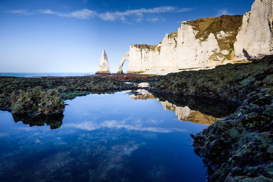 Reflection of cliffs and needle rock in tidal pools of Etretat in Normandy France during low tide