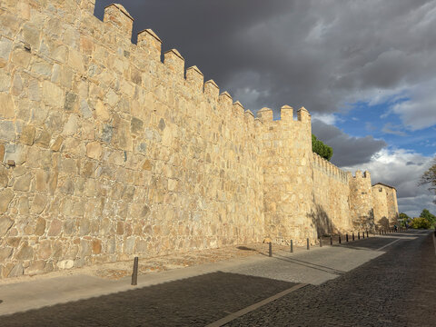 City walls showcase historic stone structure along street in Avila, Extremadura, Spain during cloudy weather