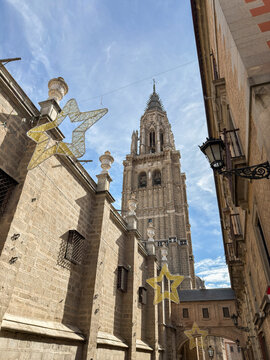 Cathedral tower stands tall above narrow street adorned with decorative stars in Toledo, Castilla-La Mancha, Spain