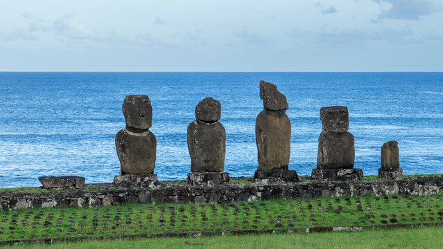 Moai statues stand at Ahu Tahai Ceremonial Complex against the ocean on Easter Island in Chile during a bright day