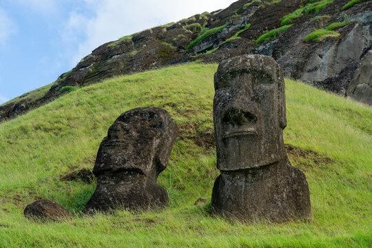 Moai statues stand on a grassy slope of Rano Raraku quarry on Easter Island in Chile
