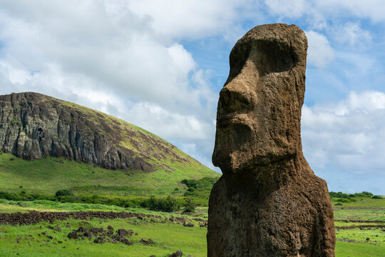 Mysterious moai stands strong on Easter Island with volcanic hill in the background under a cloudy sky
