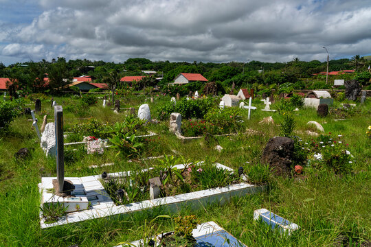 Exploring Hanga Roa cemetery on Easter Island with many graves surrounded by greenery and local houses
