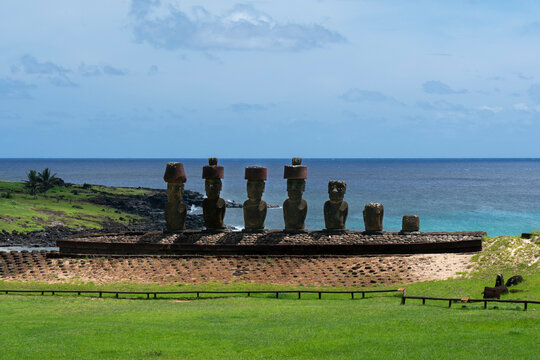Moai statues stand on the beach at Anakena with the ocean in the background and green land around them in Rapa Nui, Chile