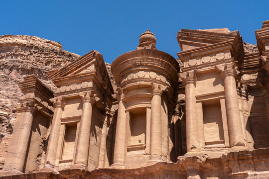 Monastery structure stands tall in the desert landscape of Petra in Jordan under a clear blue sky