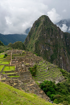 Exploring the ruins of an ancient Inca city on a mountain in Peru with green terraces and cloudy skies