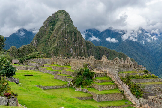 Machu Picchu shows ancient ruins and green landscape with mountain backdrop in Peru during cloudy weather