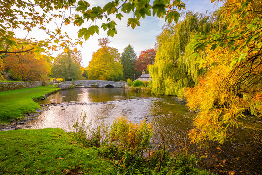 View of Sheepwash Bridge over River Wye in autumn with trees and water in Derbyshire
