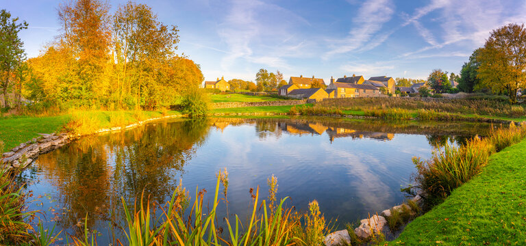 Reflections in village pond during autumn in Monyash village, Bakewell, Derbyshire Peak District, UK